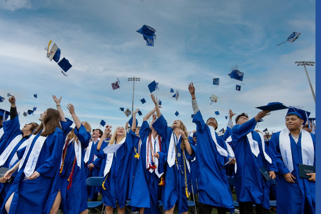 Los graduados, ataviados con togas y birretes azules, lanzan alegremente sus birretes al aire durante la ceremonia de graduación.