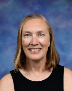 A smiling woman with shoulder-length hair, wearing a black top, against a blue and purple background.