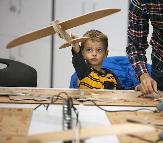 Alumno de jardín de infancia con maqueta de avión en STEM night