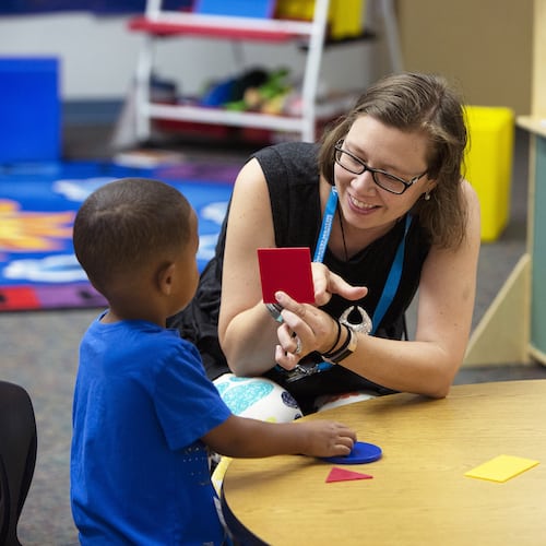 Un profesor muestra una tarjeta a un alumno de preescolar.